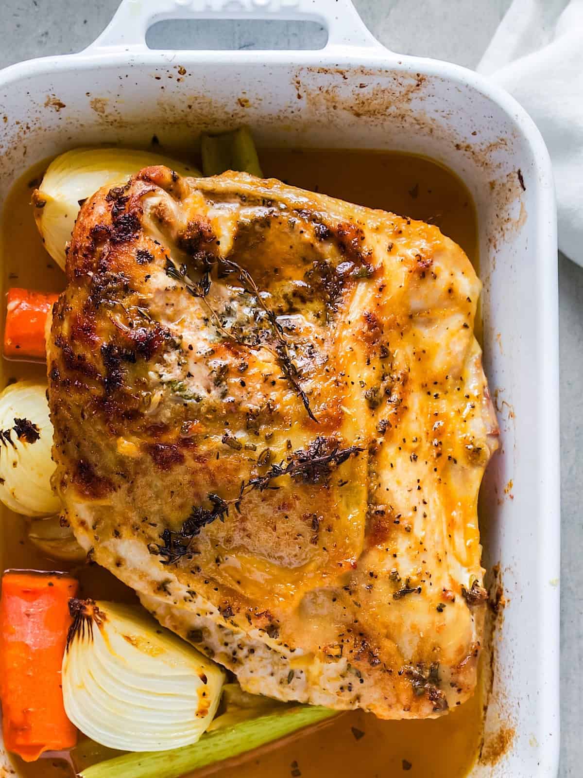 Herb roasted turkey breast in casserole dish with potatoes, celery, and onion.