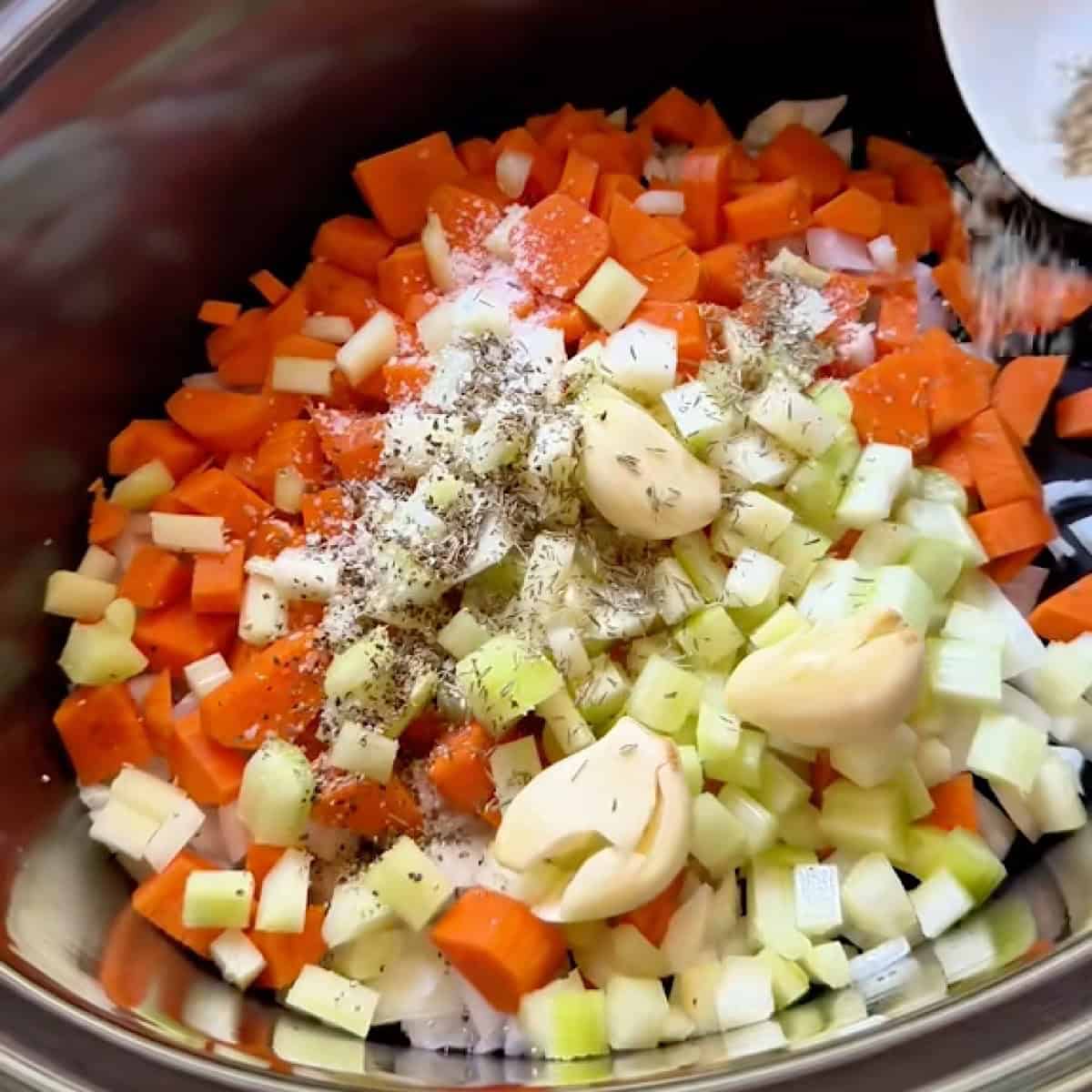 Adding butter, vegetables, and garlic to the slow cooker.