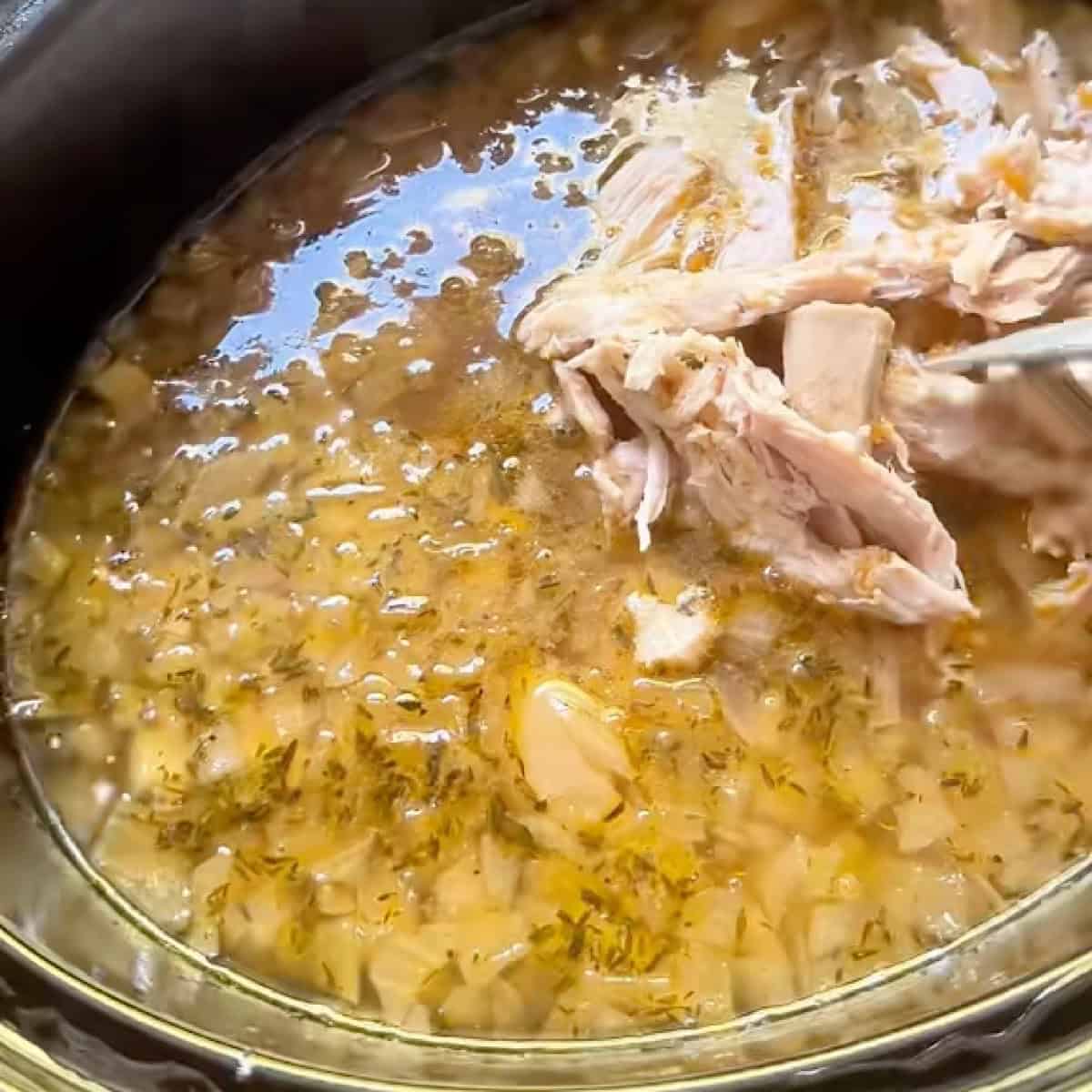 Adding the leftover turkey to the crockpot.