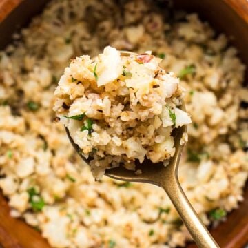 A gold spoon with lemon herb cauliflower rice showing the texture.