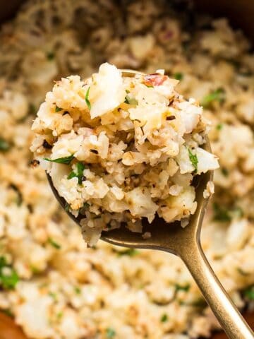 A gold spoon with lemon herb cauliflower rice showing the texture.
