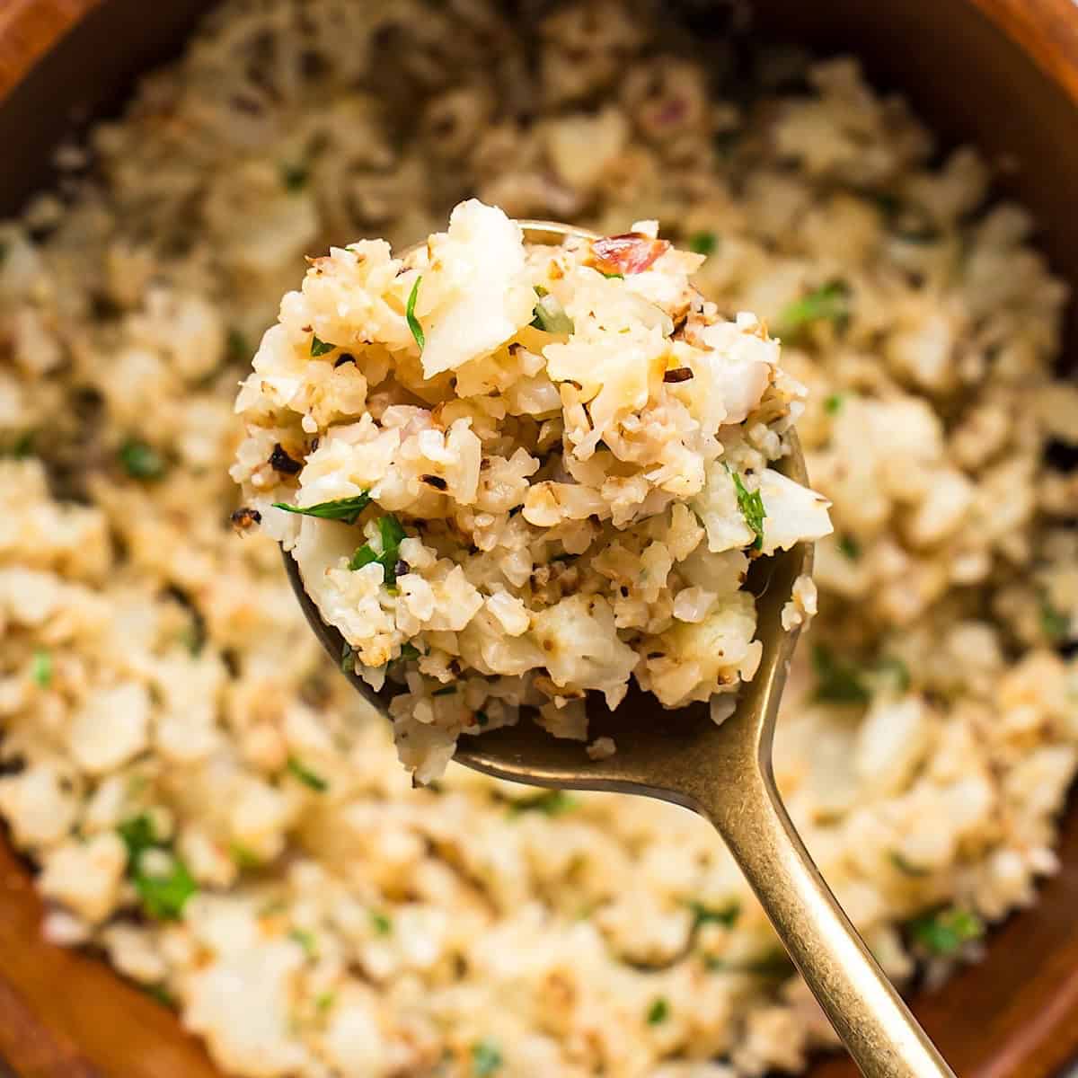 A gold spoon with lemon herb cauliflower rice showing the texture.