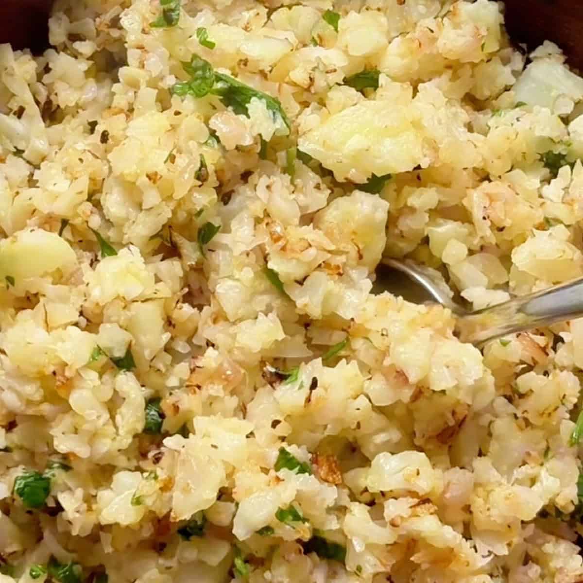 Cauliflower rice in a bowl finished with parsley and lemon.