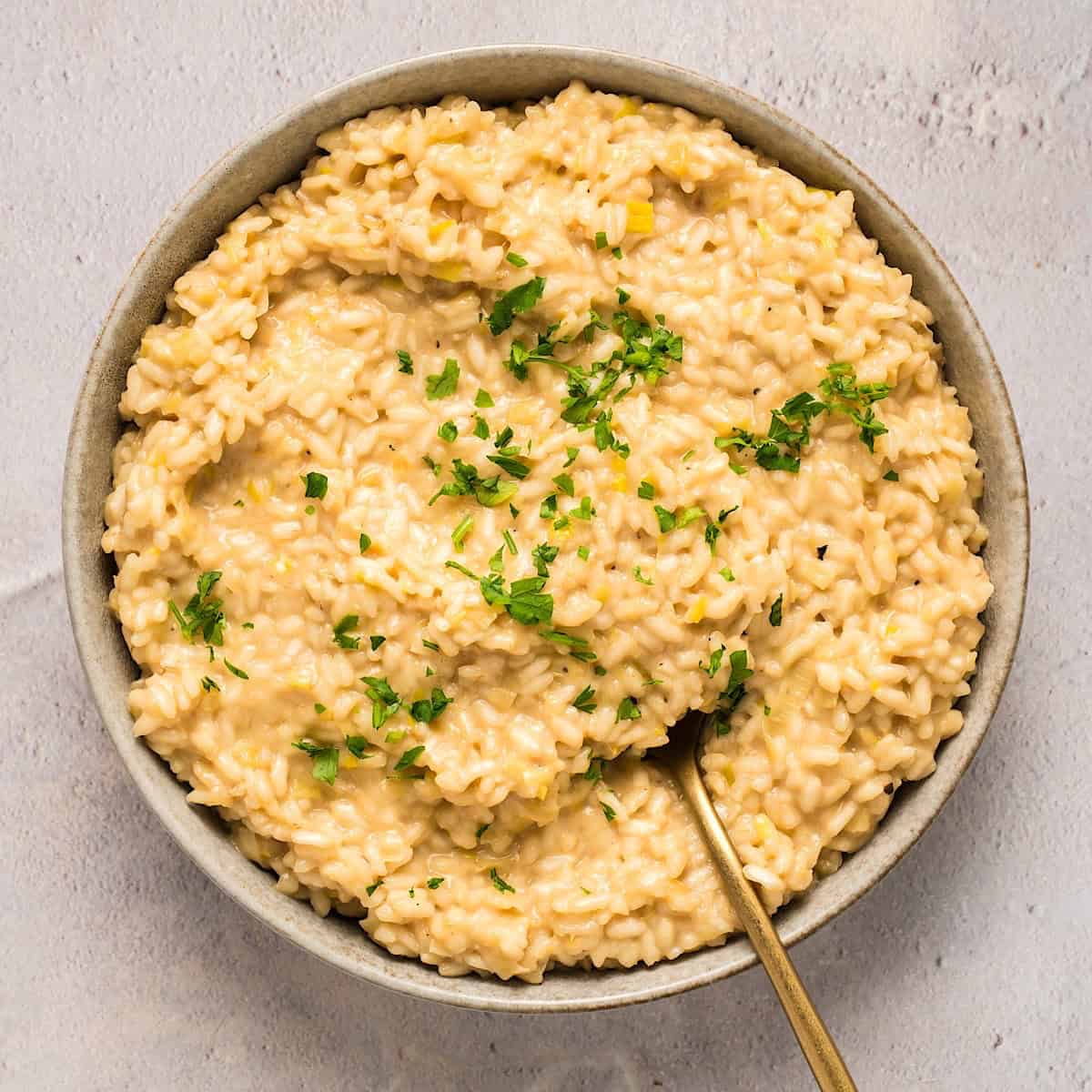 A wide shallow bowl of roasted garlic and leek risotto.