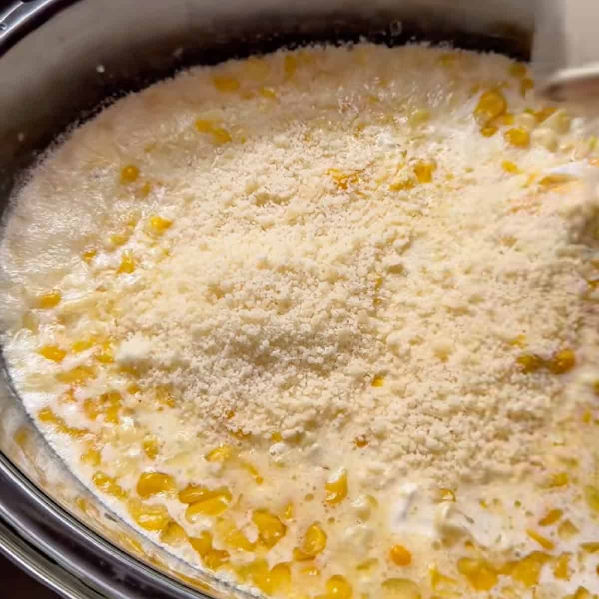 Parmesan sprinkled on top of the corn in the slow cooker.