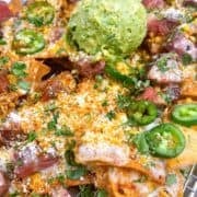 Steak elote nachos on a sheet pan with queso and guacamole.