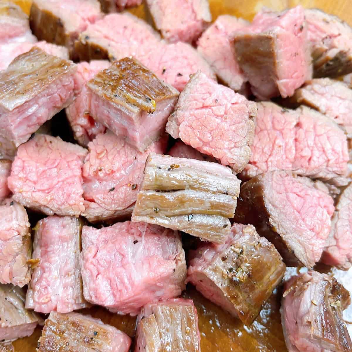 Cooked flank steak chopped into small, bite-sized pieces.