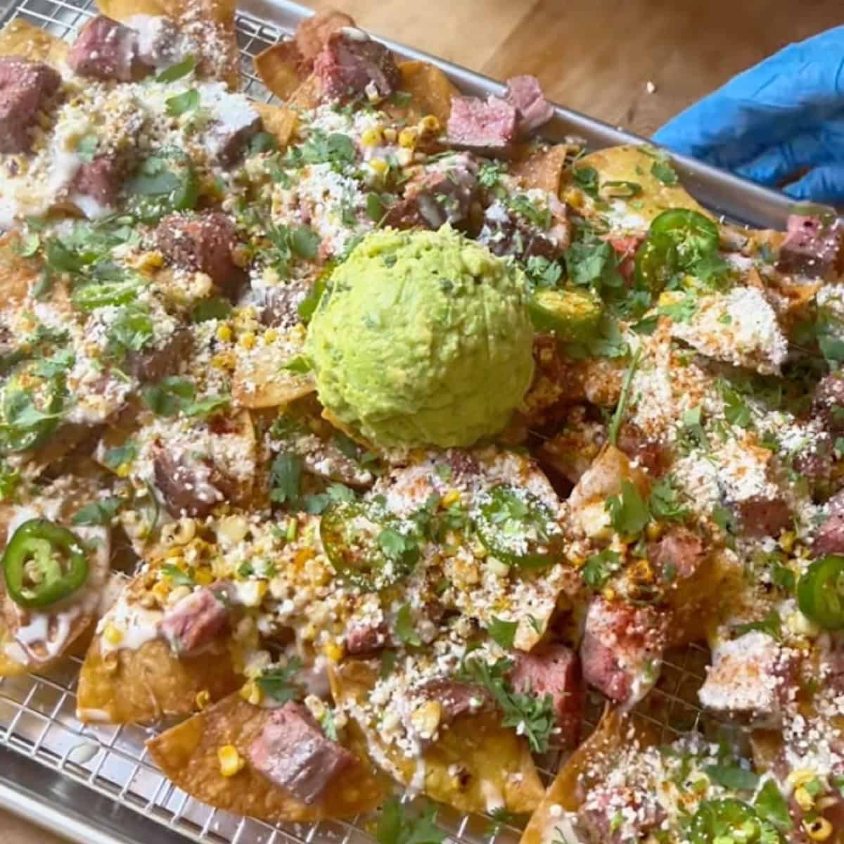 Flank steak elote style nachos on a sheet pan loaded and ready to serve.