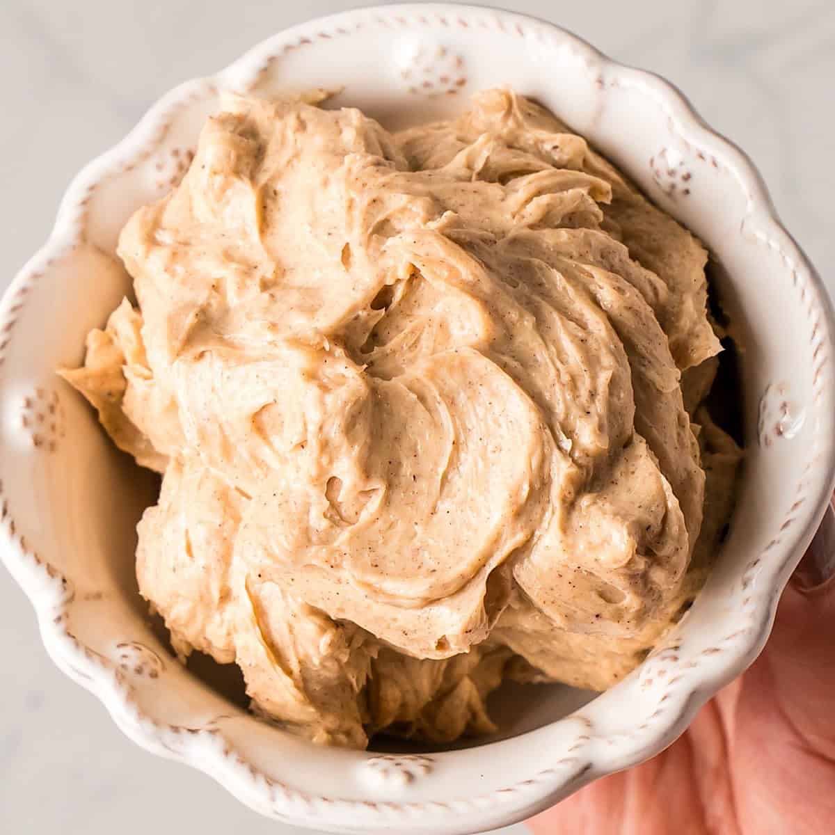 Holding fluffy whipped brown sugar cinnamon butter in a decorative bowl.