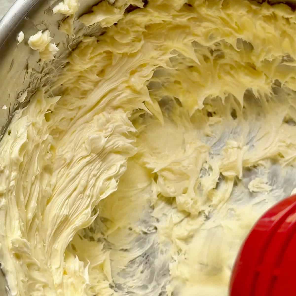 Whipped light and fluffy butter collecting on the side of the mixing bowl.
