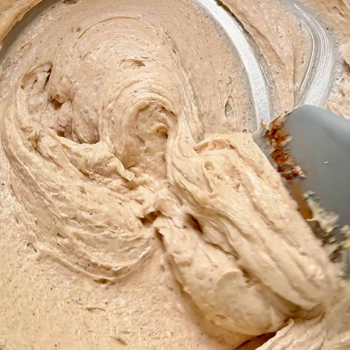 Silicon spatula lifting the whipped butter out of the bowl to show consistency.