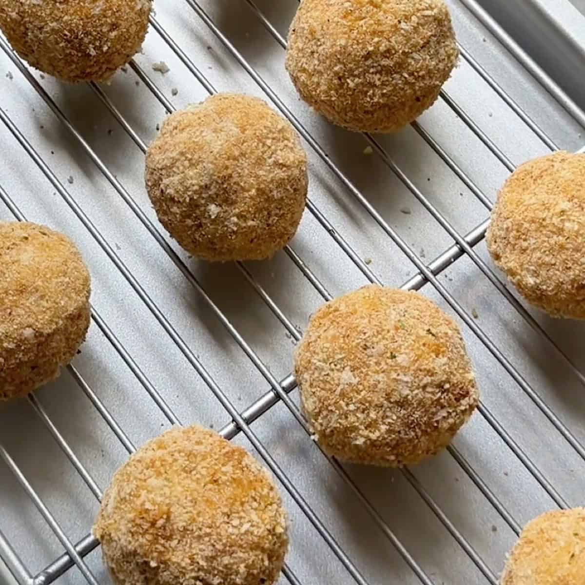 Breaded arancini on a tray ready to chill in the refrigerator.