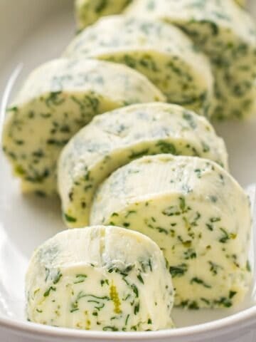 Sliced cilantro lime compound butter in a butter dish.