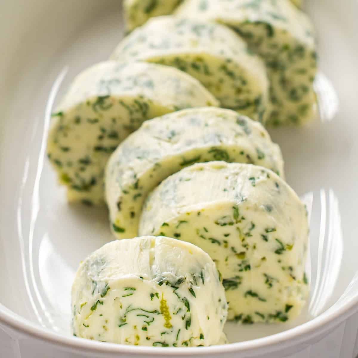 Sliced cilantro lime compound butter in a butter dish.