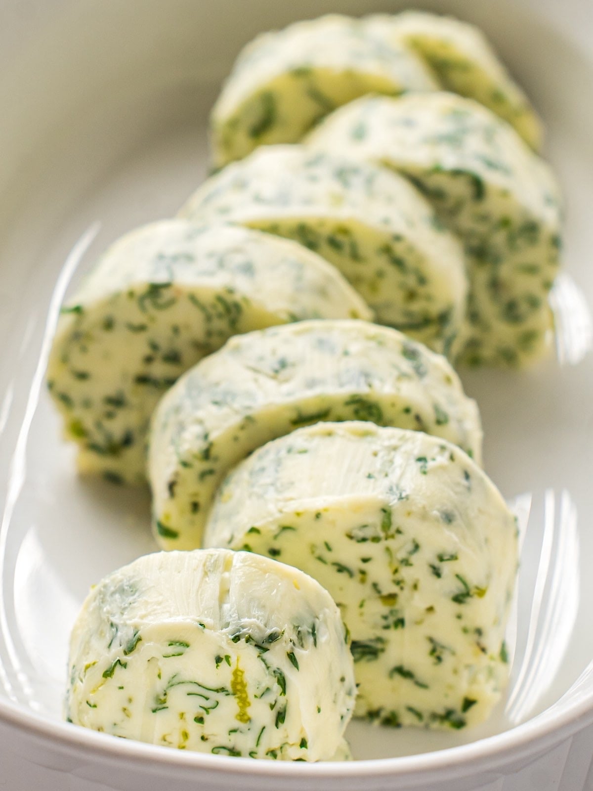 Sliced cilantro lime compound butter in a butter dish.