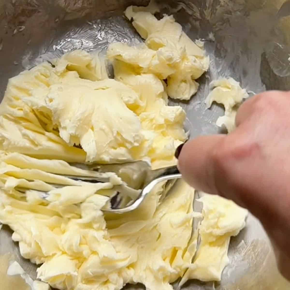 Using a fork to mash the softened butter.