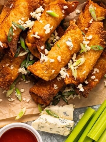 Buffalo egg rolls on a platter with blue cheese, ranch, and celery.