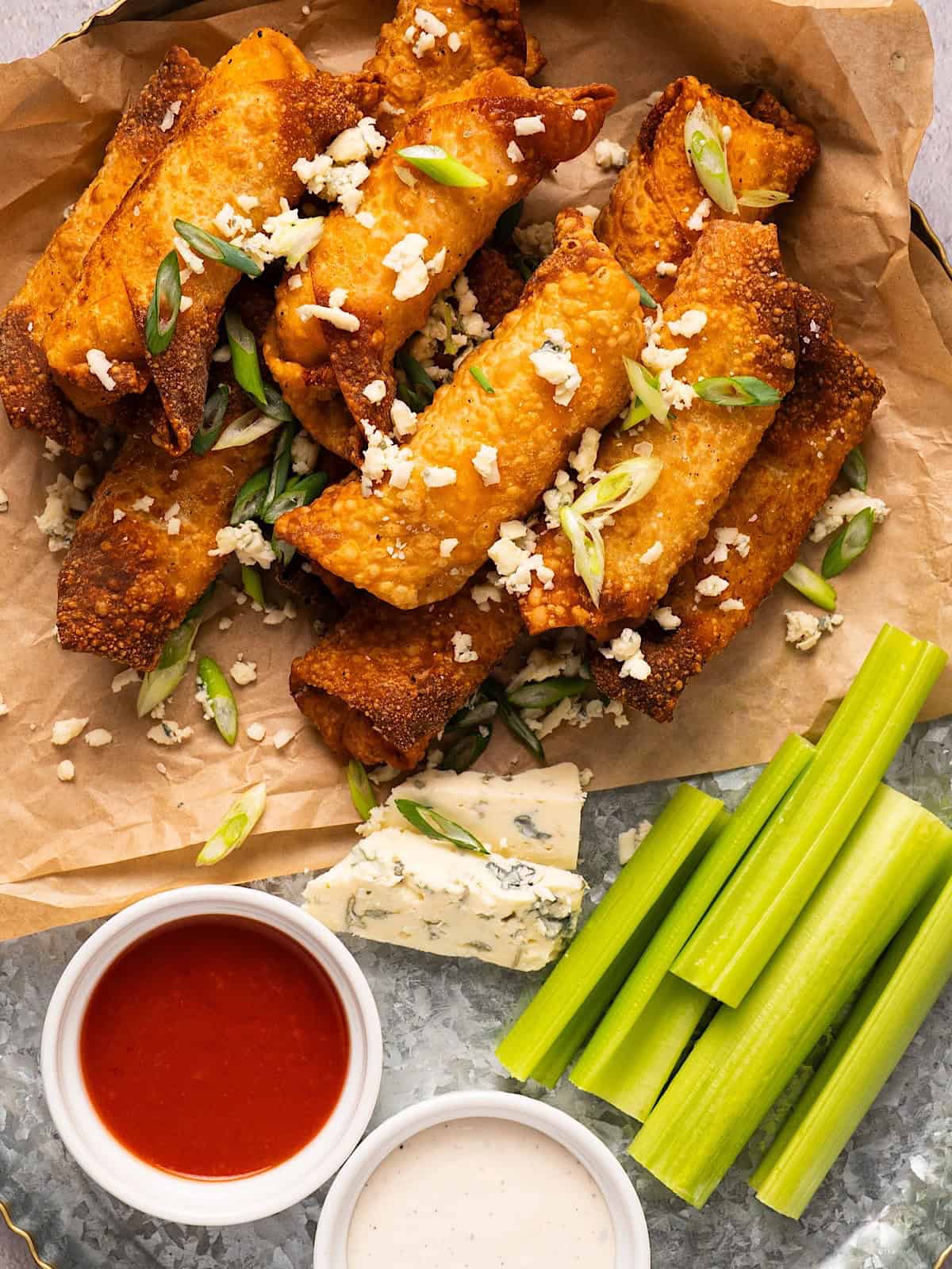 Buffalo egg rolls on a platter with blue cheese, ranch, buffalo sauce, and celery.