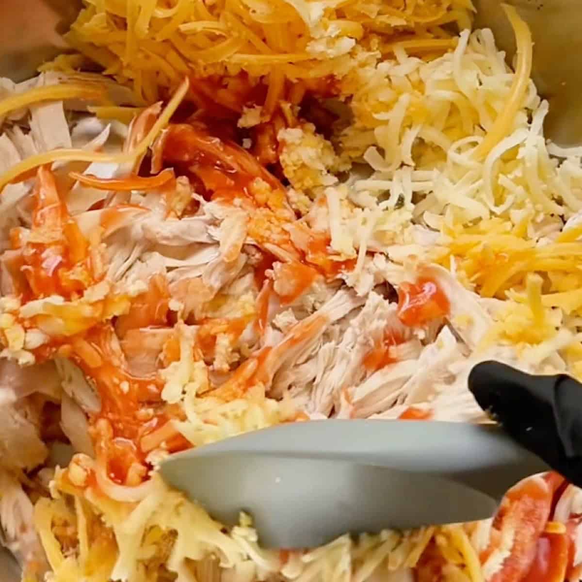 Mixing the buffalo chicken egg roll filling with a rubber spatula.
