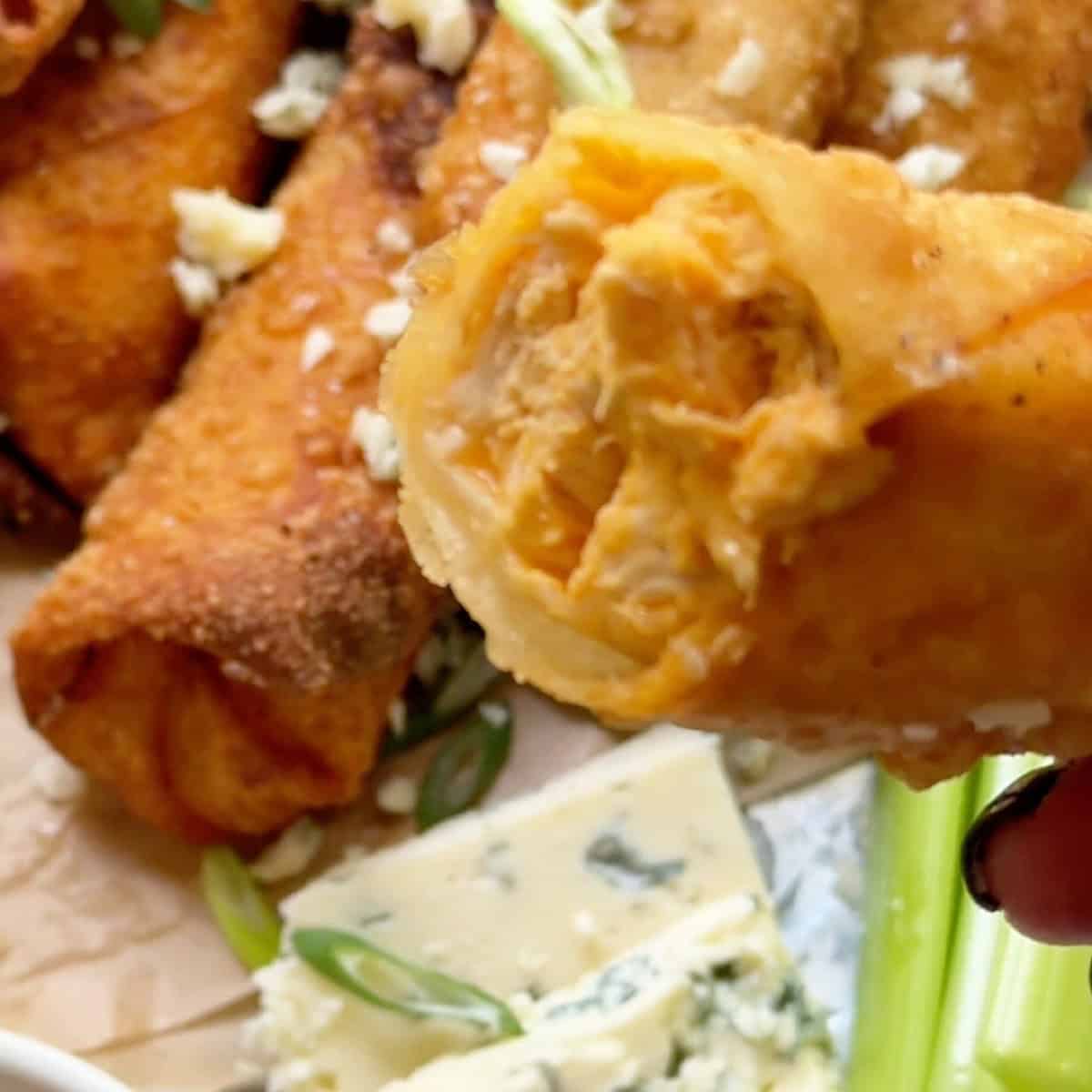 Holding an open buffalo egg roll over a garnished platter.