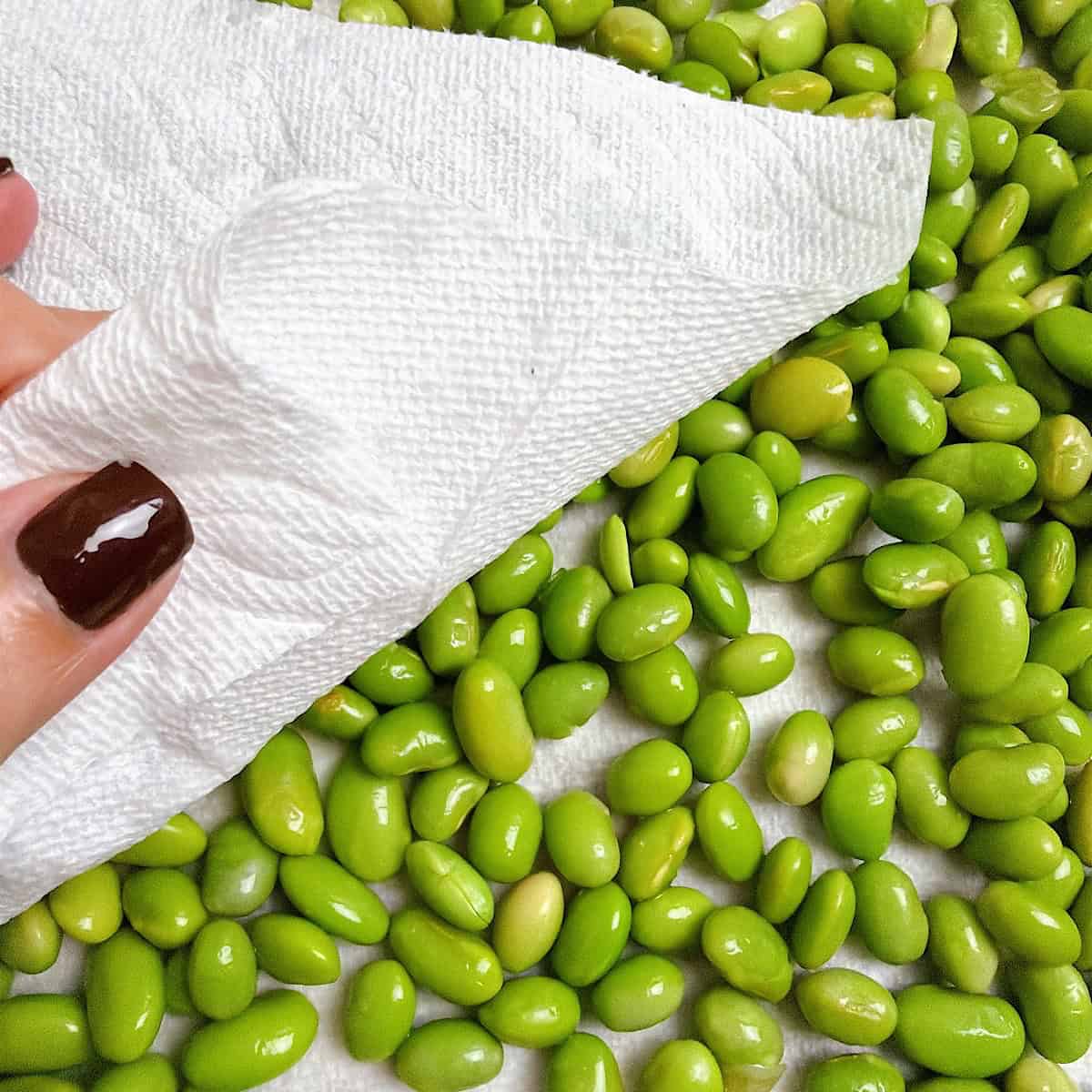 Drying the edamame that's resting on a paper towel.