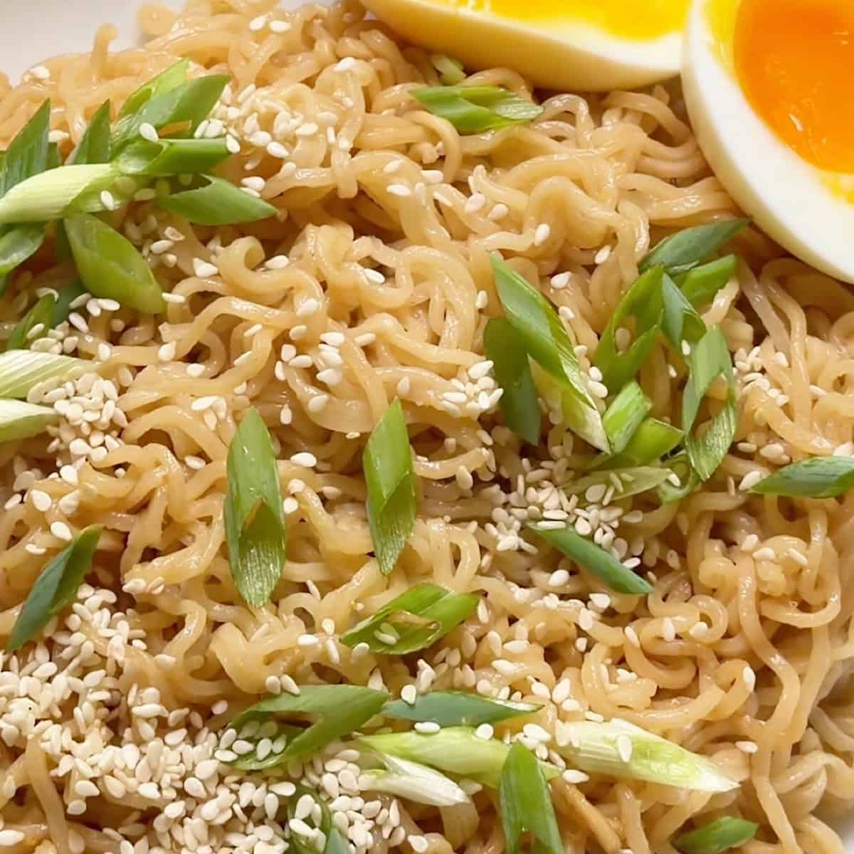 Garlic ginger ramen plated with sesame garnish and medium boiled eggs.