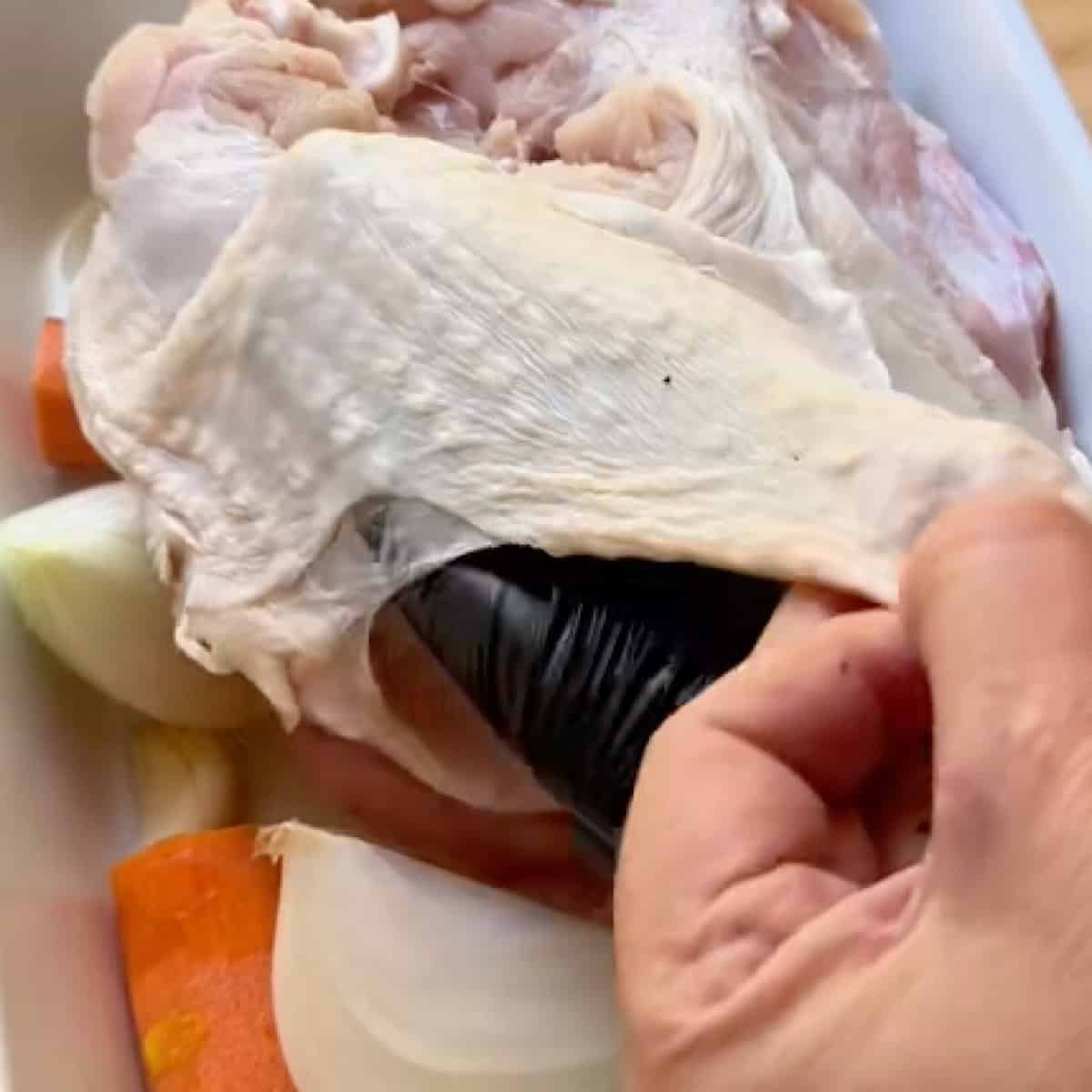 Spreading herb butter under the skin of the turkey breast.