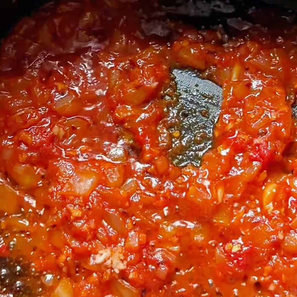 Vodka sauce being reduced with tomato paste and onions.