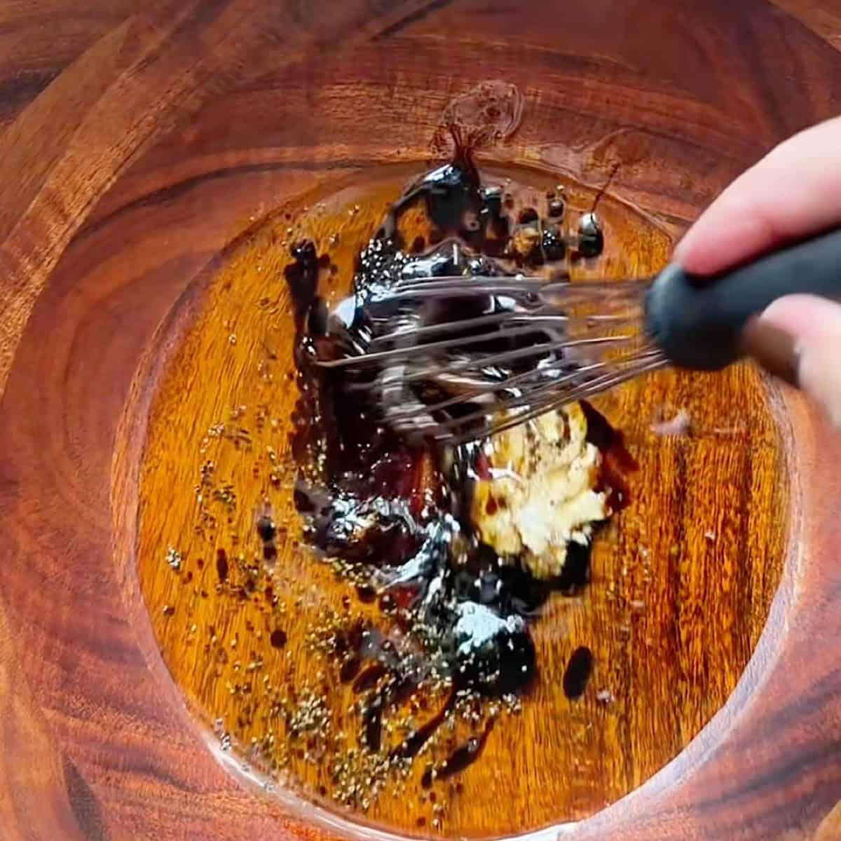 Whisking the balsamic Dijon vinaigrette dressing.