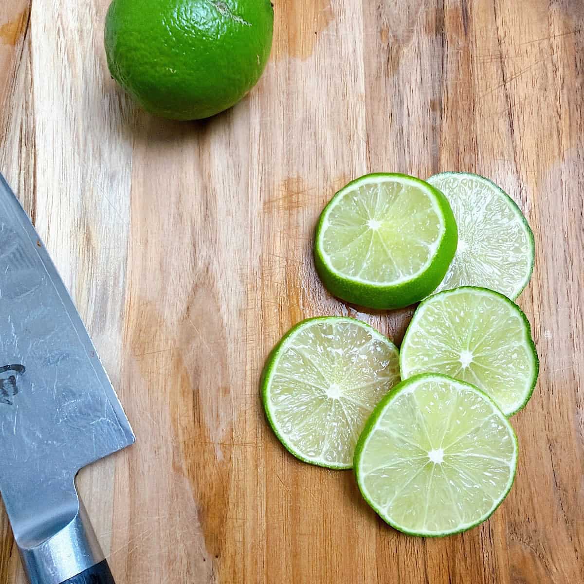 Sliced lime wheels on a cutting board.