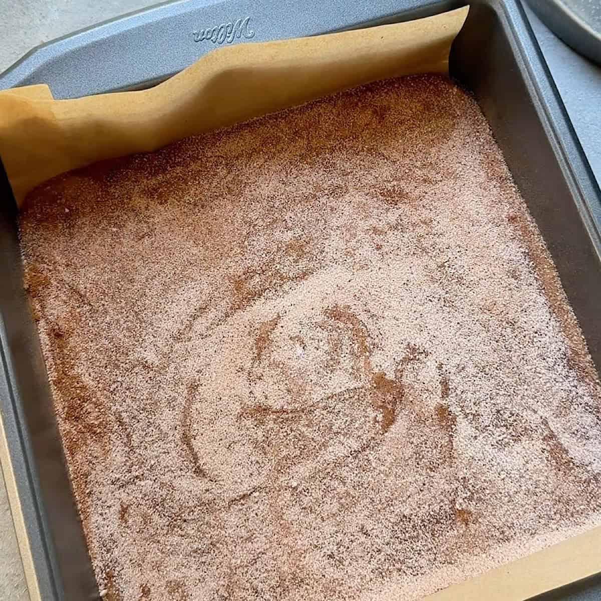Batter spread into a parchment lined 8x8 pan with cinnamon sugar topping.
