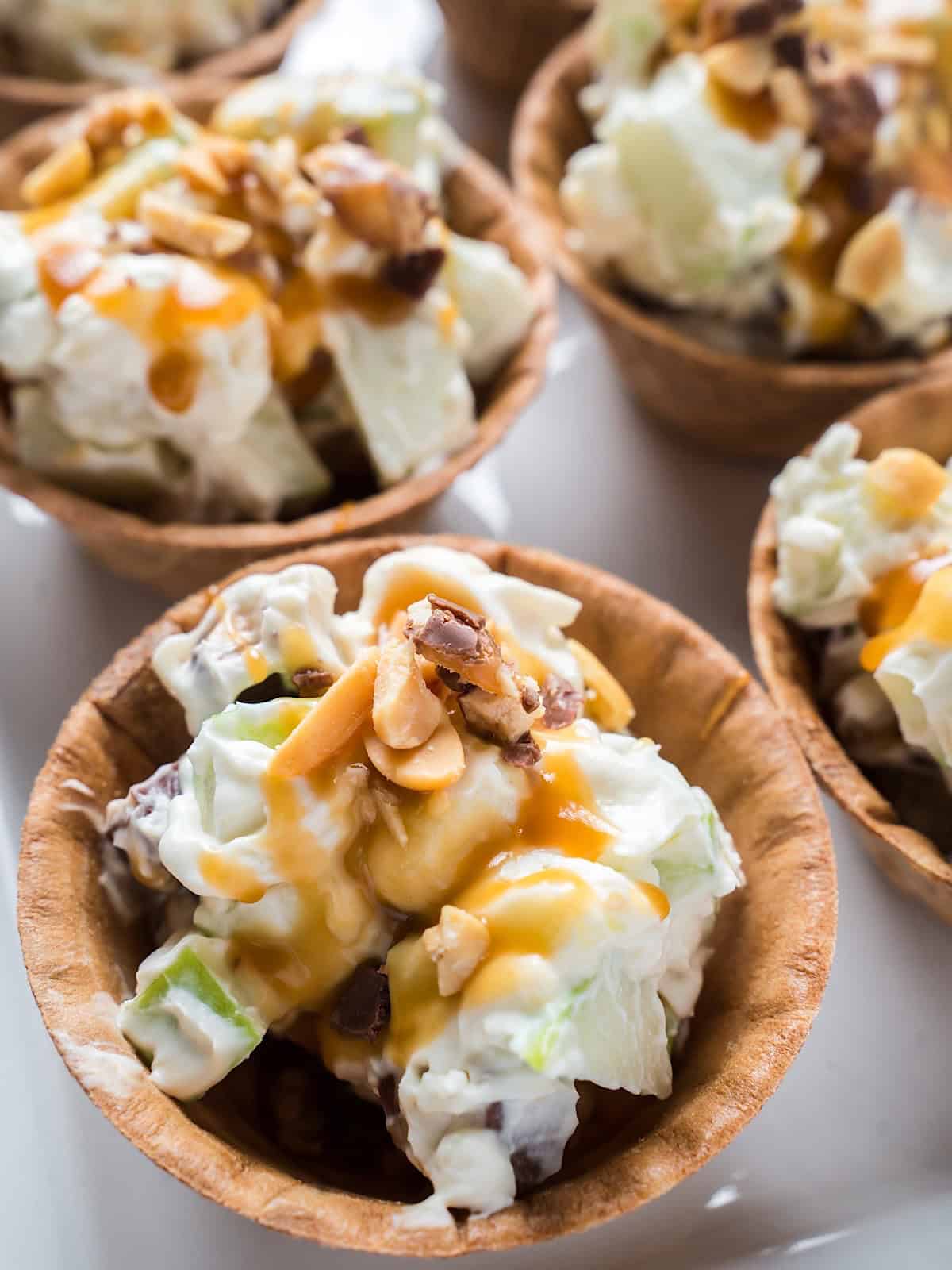 Snickers caramel apple salads in waffle bowls with toppings.
